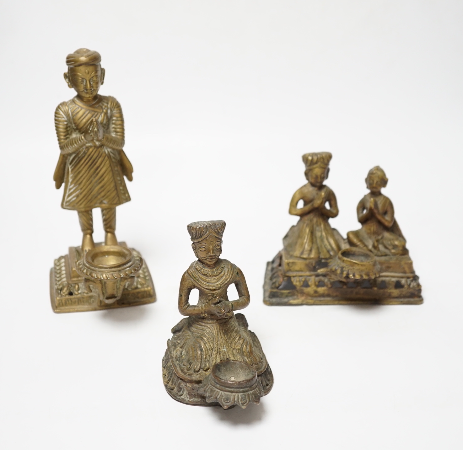 Three Nepalese figural brass oil lamps, 18th/19th century